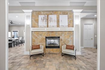 A living room with a stone fireplace and two chairs. at Somerset Oaks Apartment Homes, Kansas